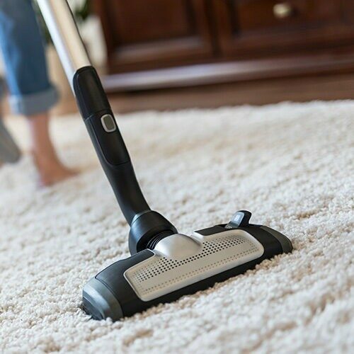 Lady using a vacuum cleaner while cleaning carpet | Valley Floor Covering Inc